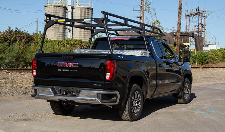 A black GMC pickup truck upfitted with a ladder rack and tool box made by Adrian Steel