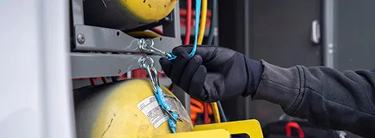 man adjusting a gas tank placed inside an Adrian Steel tank storage