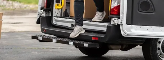 a man getting out of a work van with the help of safety steps fabricated by Adrian Steel