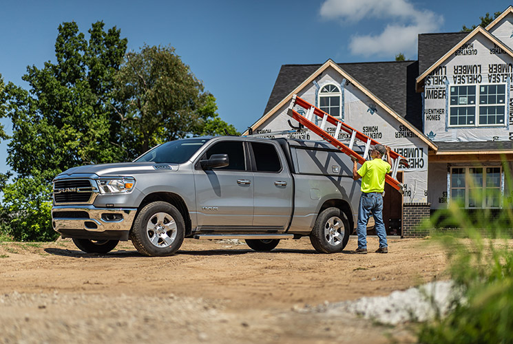 a man loading a ladder on a RAM pickup truck upfitted with an Adrian Steel ladder rack