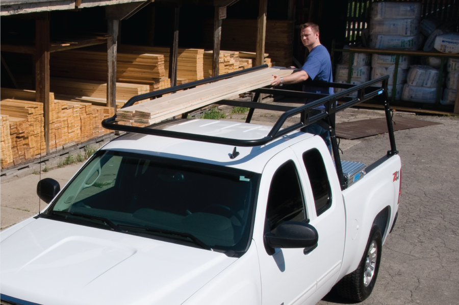 a man loading lumber on a pickup upfitted with an Adrian Steel pickup ladder rack known as the Load Runner Rack