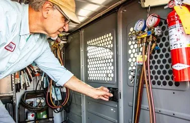 a man in the cargo area of a van full of cargo upfits, opening a door built into a steel partition that leads to the cabin