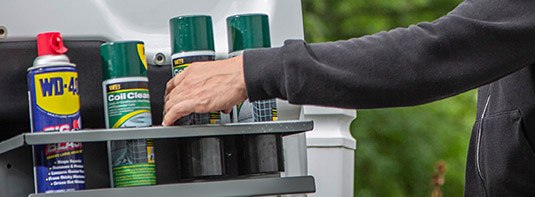 man placing a few aerosol cans in an aerosol can door holder fabricated by Adrian Steel