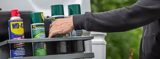 man placing a few aerosol cans in an aerosol can door holder fabricated by Adrian Steel