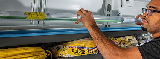 man placing a part on an Adrian Steel long parts storage solution that is installed inside a work van