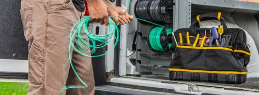 man pulling a green cable from an Adrian Steel cable and wire storage accessory installed on the back of a work van