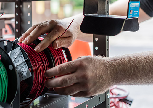 a man pulling a wire from a wire spool secured in an Adrian Steel wire reel holder