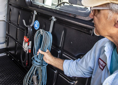 a man grabbing a cable held on a hook mounted on a van partition made by Adrian Steel