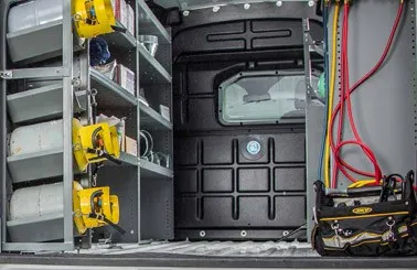 the interior of a work van equipped with an Adrian Steel composite partition and some cargo upfits